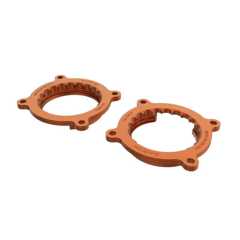 A pair of bright orange anodized aFe Silver Bullet billet aluminum throttle body spacers for 2024-2026 Ford Mustang 5.0L.