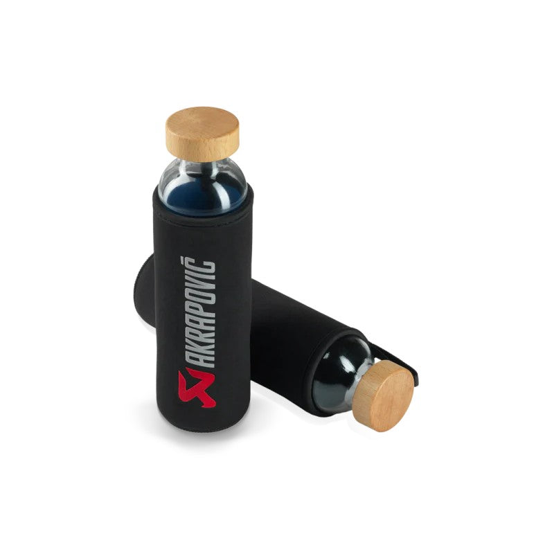 Akrapovic x Flaska glass water bottle featuring a branded protective sleeve and a wooden sealing cap.