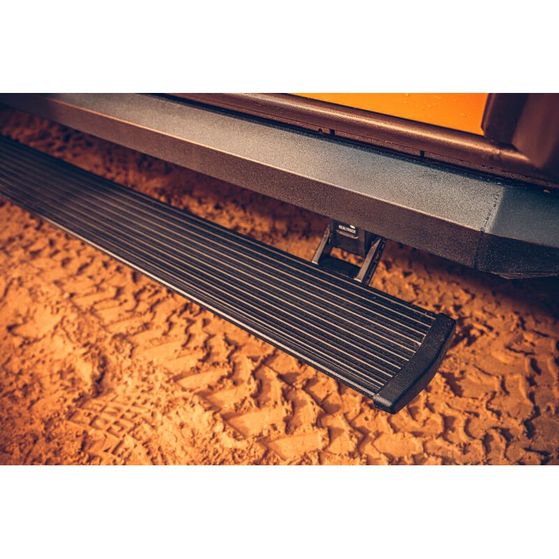 Black AMP Research PowerStep XL automatic electric running boards with LED lighting on a 2-door Jeep Wrangler JL.