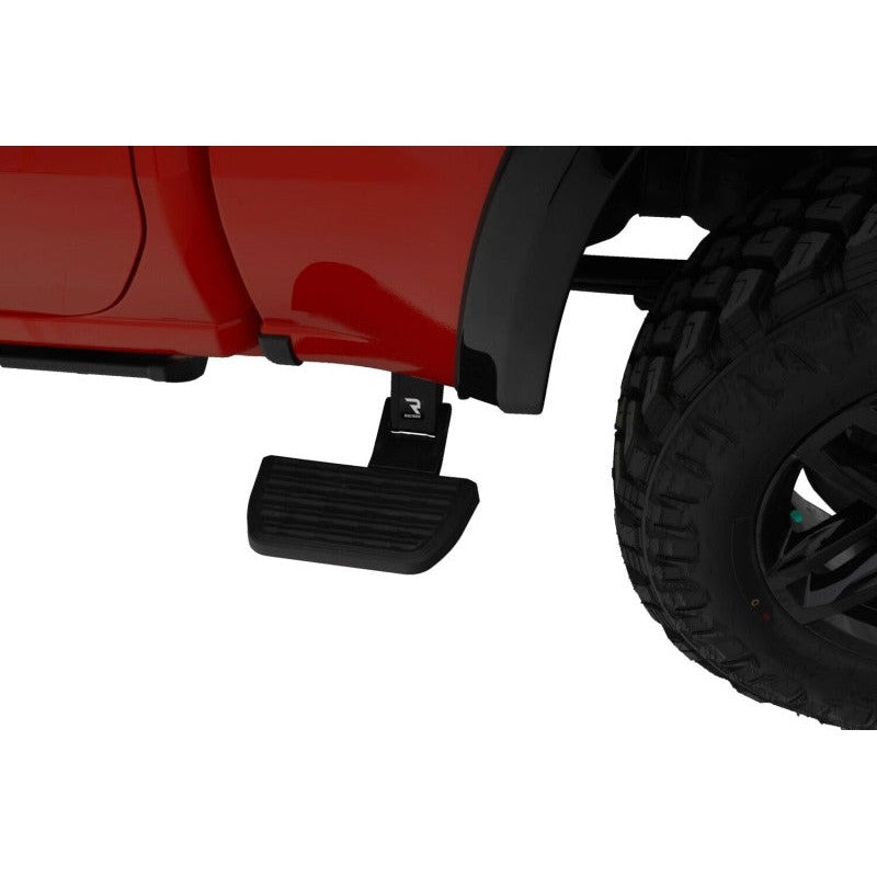 Black AMP Research BedStep2 retractable side step mounted to a truck frame behind the cab.