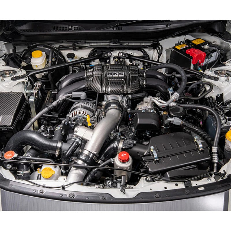 HKS GT2 centrifugal supercharger unit with black powder-coated mounting brackets and installation hardware.
