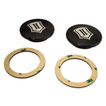 Pair of black anodized ICON billet aluminum uniball cover caps with laser-etched logos and 3M adhesive rings.