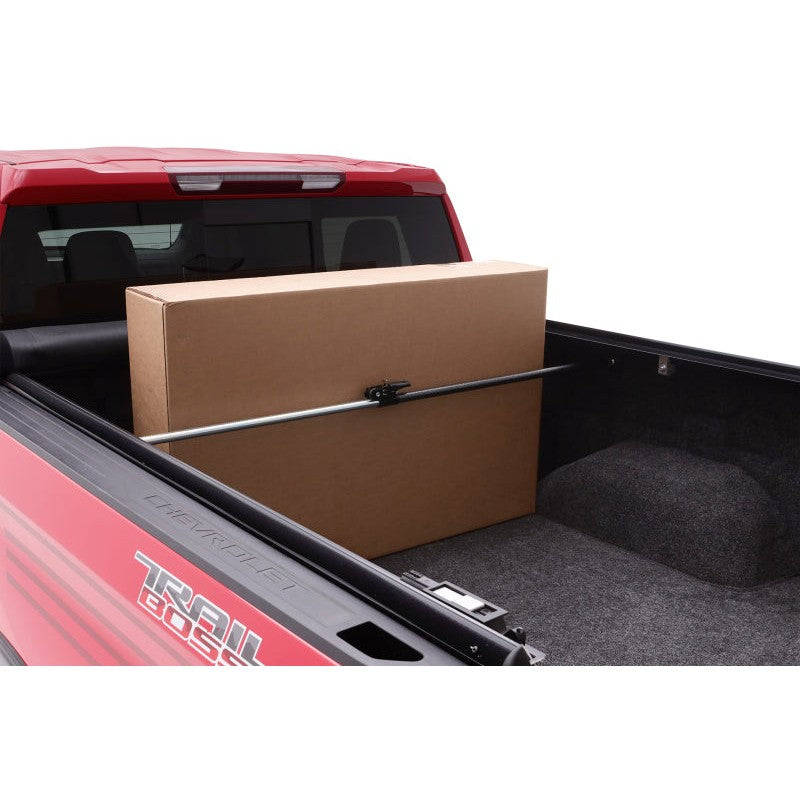 Black Lund universal ratcheting cargo bar showing adjustable 40 to 70 inch reach and protective rubber end pads.