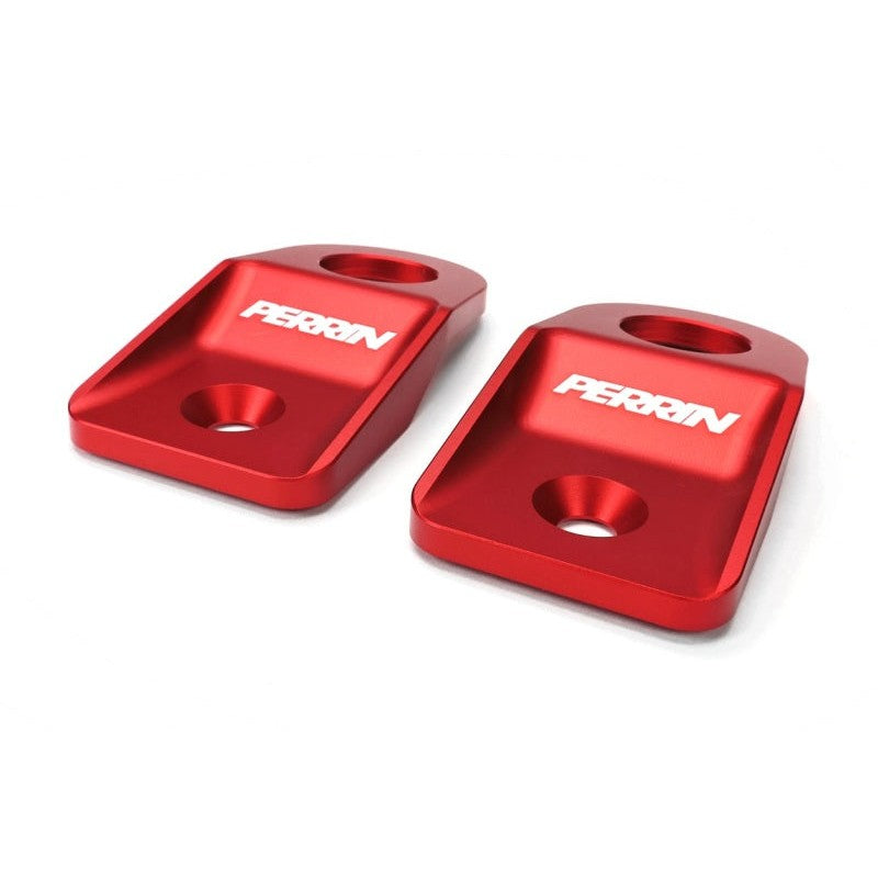 A pair of PERRIN red powder-coated aluminum upper radiator brackets for Subaru engine bays.