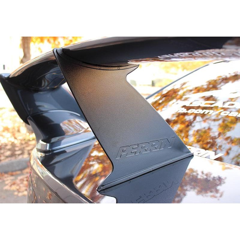 Black PERRIN wing stabilizer mounted between the trunk and rear spoiler of a 2015-2020 Subaru WRX STI