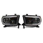 Raxiom Axial Series headlights for 2007-2013 Toyota Tundra featuring black housings, clear lenses, and LED DRL bars.