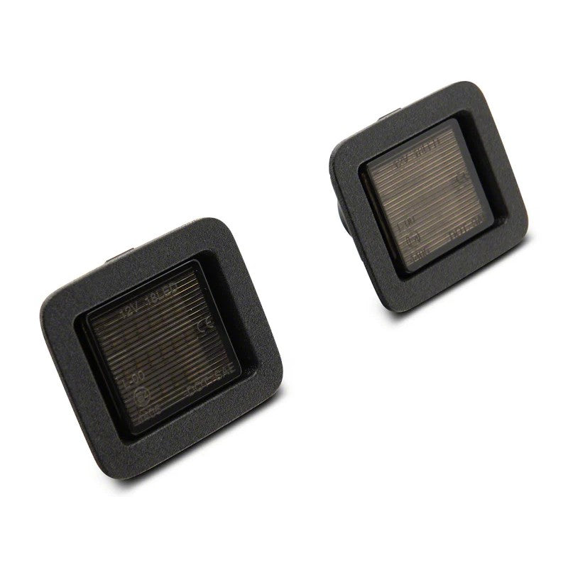 Pair of Raxiom Axial Series LED license plate lamps with smoked lenses and black housings for 2015-2024 Ford F-150.