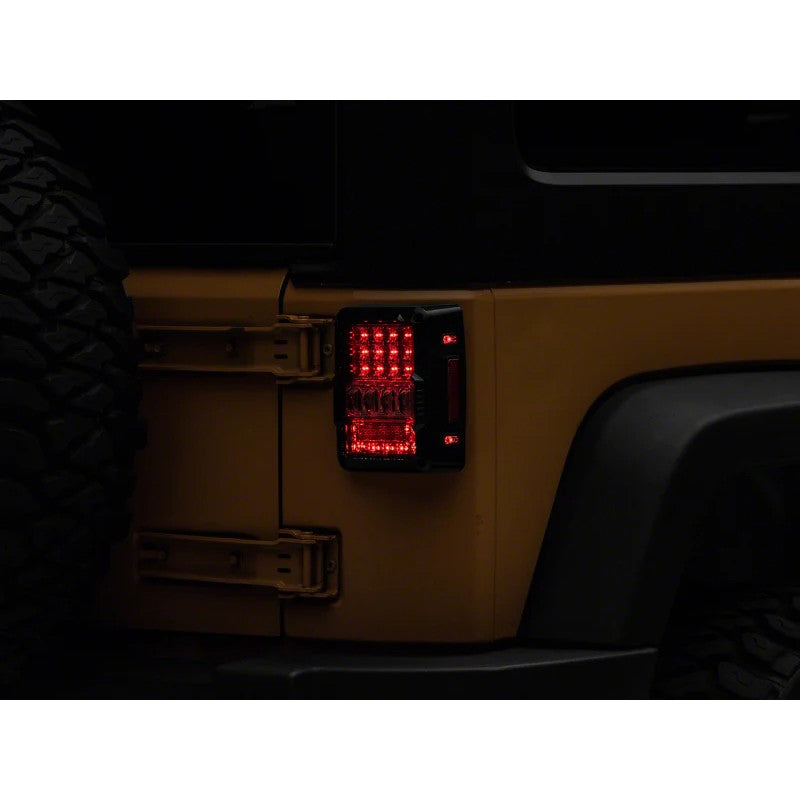 A pair of Raxiom Axial Series Lux LED tail lights for Jeep Wrangler JK with black housings and clear lenses.