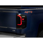 Raxiom Axial Series LED tail lights with black housing and smoked lens for Chevrolet Silverado.