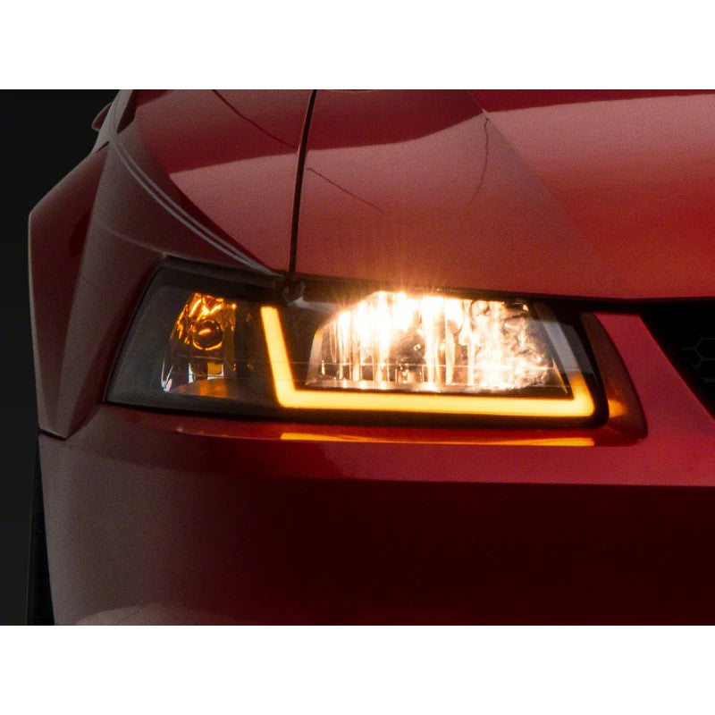Raxiom Axial Series headlights with black housings, clear lenses, and integrated LED DRL bar for 1999-2004 Ford Mustang