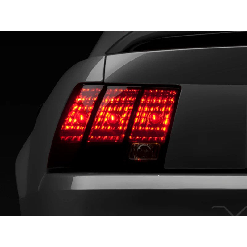 Raxiom tail light set for 1999-2004 Ford Mustang featuring dark smoked lenses and black internal housings.
