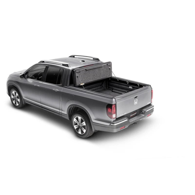 Matte black UnderCover Ultra Flex hard folding truck bed cover installed on a pickup truck bed showing three panels.