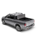 Matte black UnderCover Ultra Flex hard folding truck bed cover installed on a pickup truck bed showing three panels.